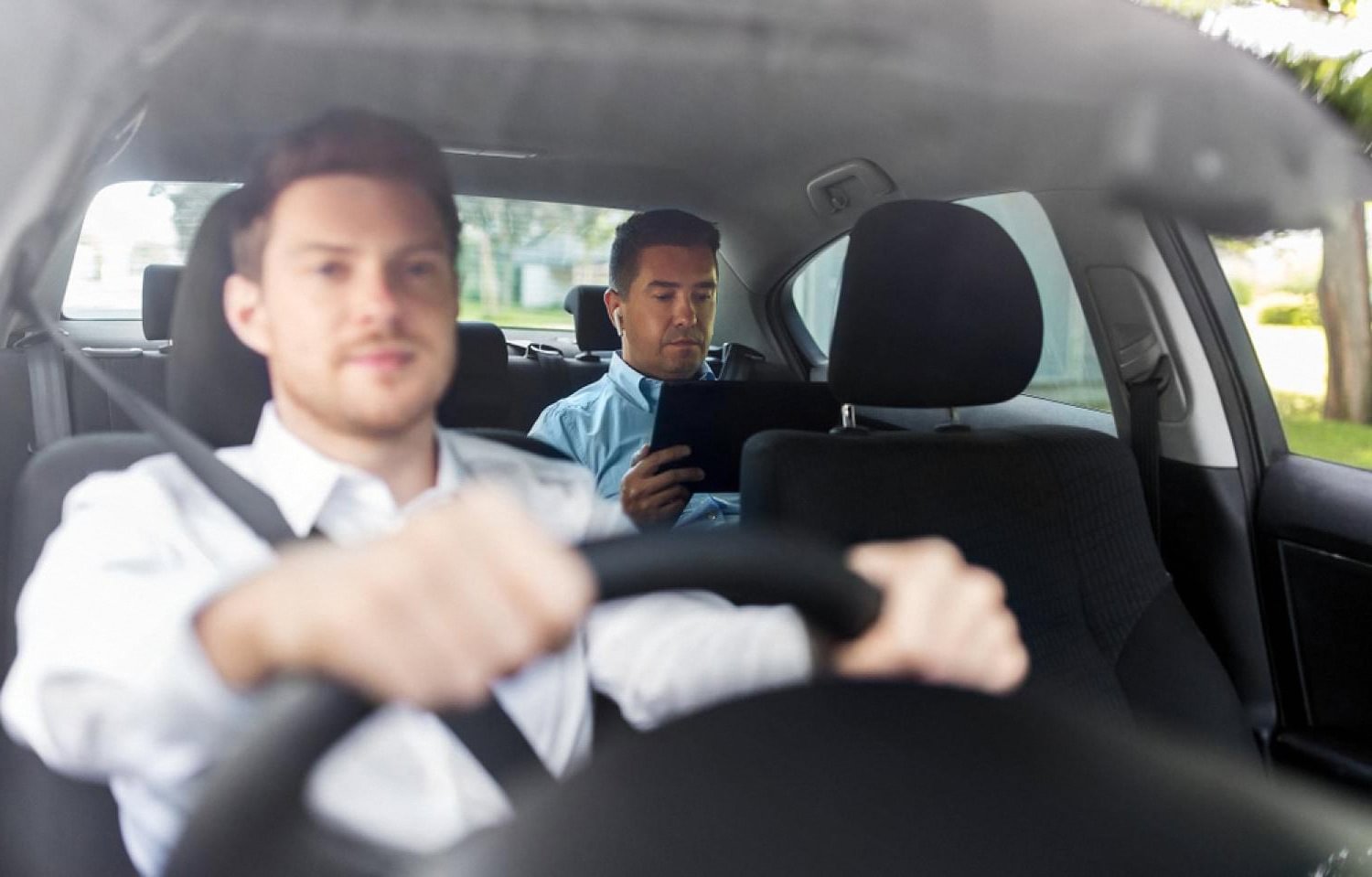 Chauffeur driving a business passenger working on a tablet in Dubai