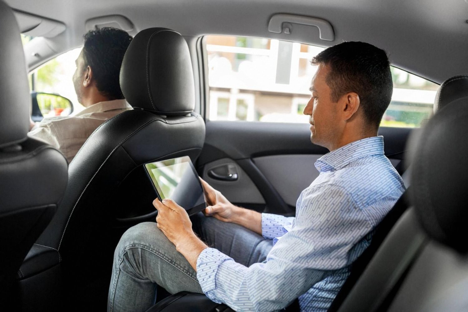 Executive using a tablet in the back of a chauffeur-driven car in the UAE